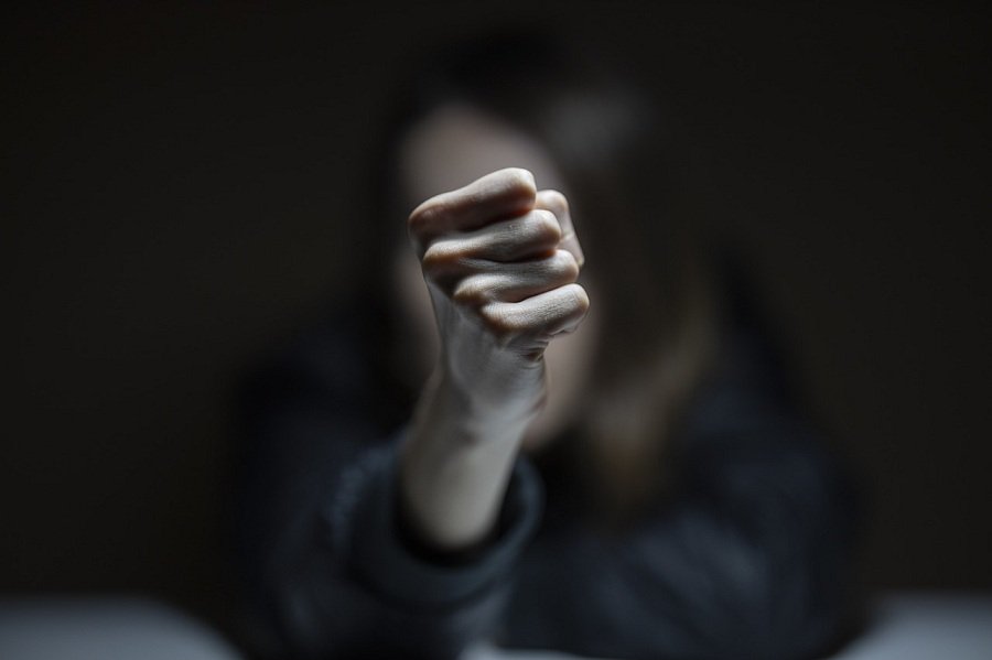 „Илустрација за семејно насилство – загрижена жена во темна просторија, симболизирајќи страв и загрозеност во домашното насилство.“